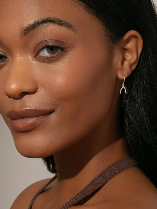 Pendientes Huggie con forma de hueso de la suerte y pavé