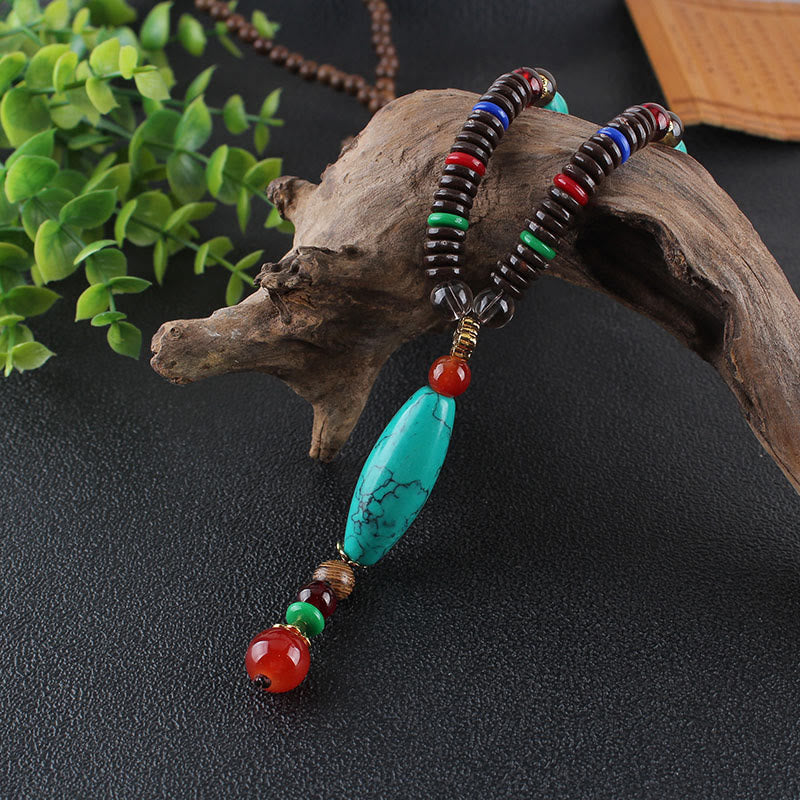 Collar con colgante de piedra turquesa, madera de wengué y piedras de Buda que protegen la calma.