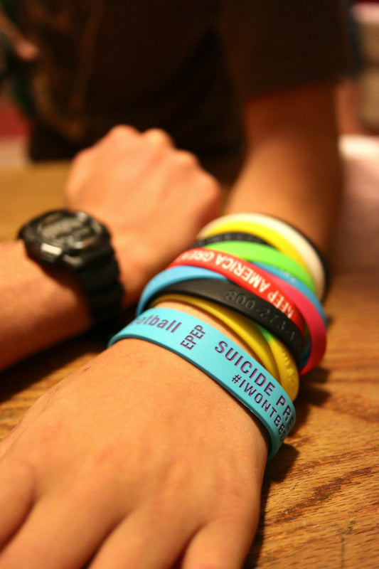person wearing multiple silicone bands and watch