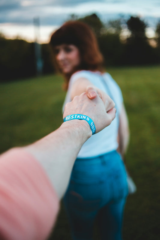 woman reaching hand of another person while standing on green field