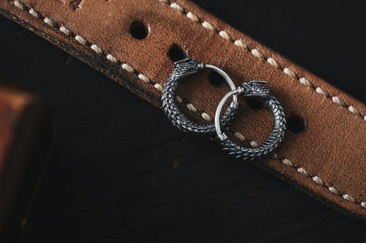 a pair of silver rings sitting on top of a brown leather belt