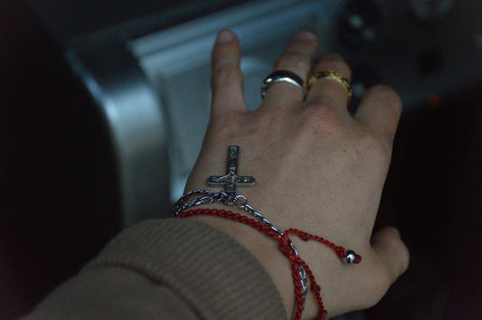 a person wearing bracelets and a cross on their wrist