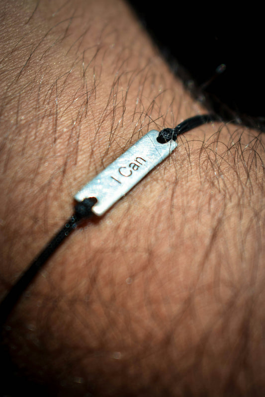 A man's arm with a bracelet with a name tag on it