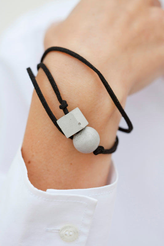 A person wearing a white shirt and a black cord bracelet
