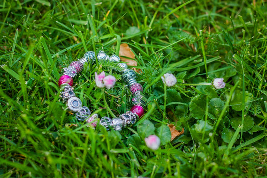 A bracelet lays gracefully in green grass.