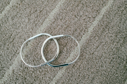 Two silver bracelets on a textured surface