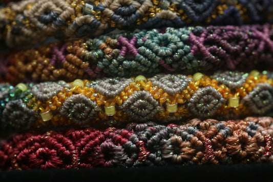Stack of colorful woven bracelets with intricate patterns.