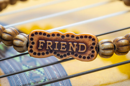 A beaded friend bracelet resting on guitar strings