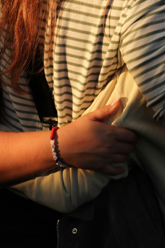 A person in a striped shirt wearing a beaded bracelet in golden hour light