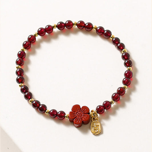 Pulsera Buddha Stones de oro de 14 quilates con flor de cinabrio y granate natural.