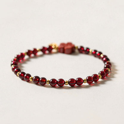Pulsera Buddha Stones de oro de 14 quilates con flor de cinabrio y granate natural.