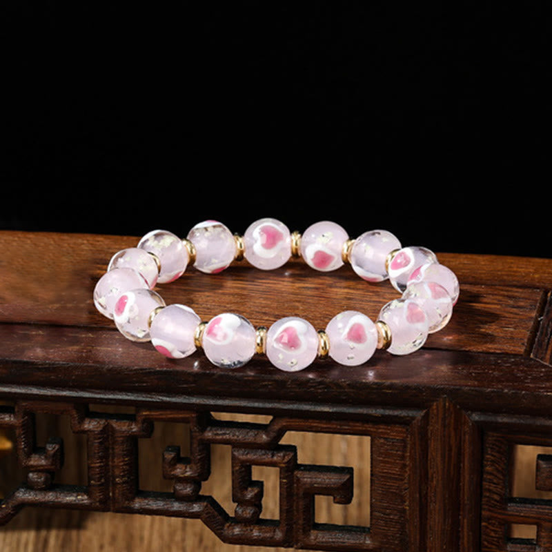 Pulsera de cuentas de vidrio fluorescentes Liuli con corazón de amor rosa y piedras de Buda doradas.