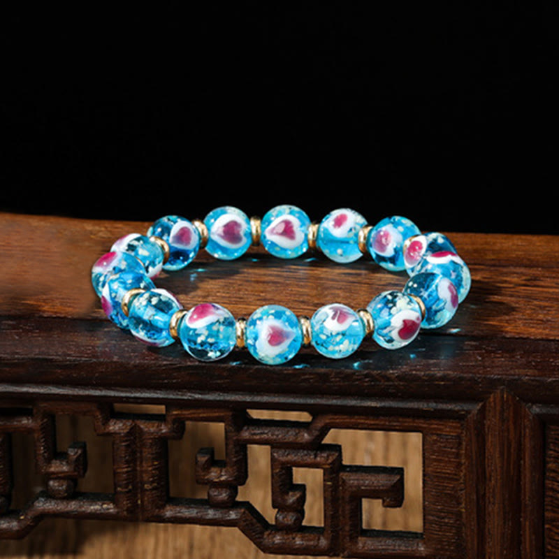 Pulsera de cuentas de vidrio fluorescentes Liuli con corazón de amor rosa y piedras de Buda doradas.