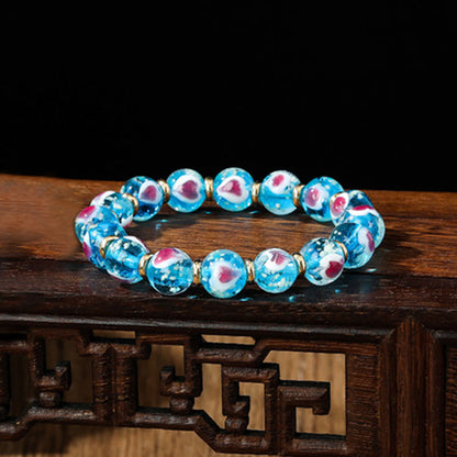 Pulsera de cuentas de vidrio fluorescentes Liuli con corazón de amor rosa y piedras de Buda doradas.