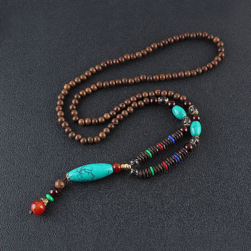 Collar con colgante de piedra turquesa, madera de wengué y piedras de Buda que protegen la calma.