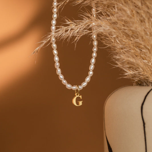 Collar con inicial de perla con boletín informativo
