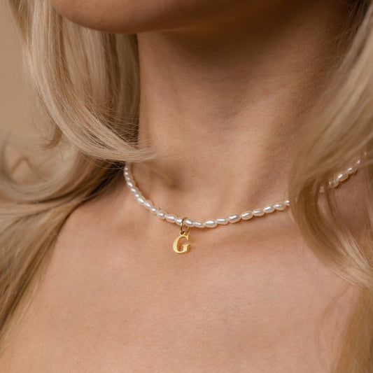 Collar con inicial de perla con boletín informativo